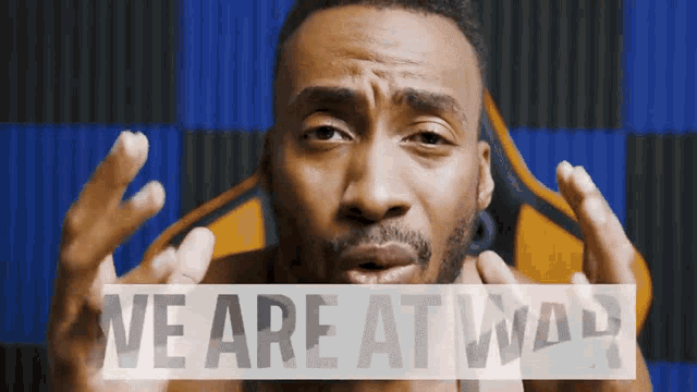 a man in front of a blue and yellow background with the words we are at war