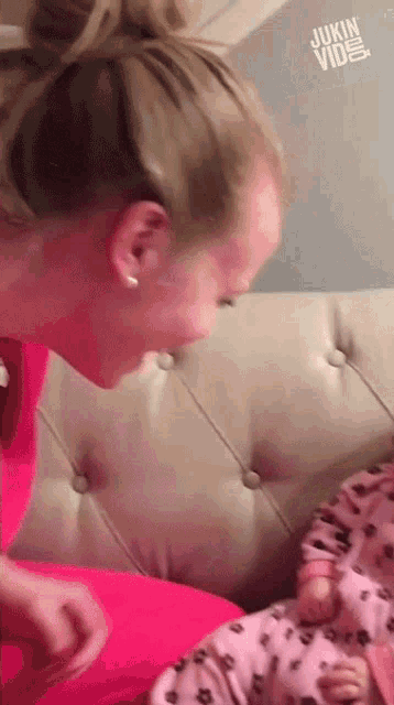 a woman is playing with a baby on a couch and the baby is wearing pink pajamas .