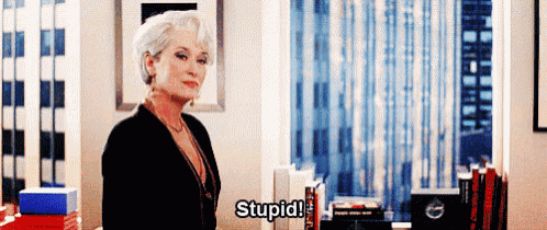 a woman in a black jacket is standing in a room and saying stupid .