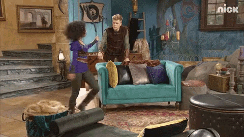 a man and a woman are standing in a living room with a nick logo on the wall