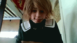 a young girl with short blonde hair is wearing a black sweater and a white collar