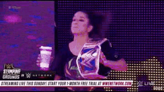 a woman is holding a cup of coffee and a wrestling championship belt .