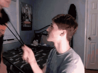 a young man is sitting on a bed with a poster on the wall behind him