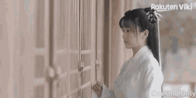 a woman in a white dress is standing in front of a door .
