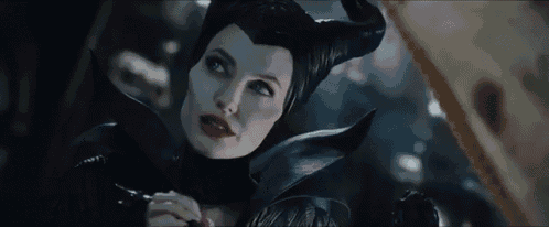 a close up of a woman wearing a black costume with horns and red lips .