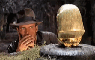 a man in a fedora is covering his mouth next to a gold object