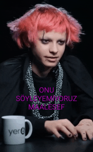 a woman with pink hair is sitting in front of a mug that says yerc