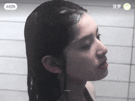 a woman is taking a shower in a bathroom with chinese writing on the wall behind her