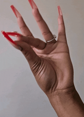 a woman 's hand with long red nails and a silver ring on her finger