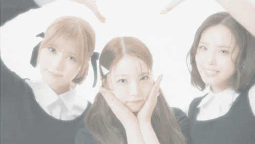 three girls are posing for a picture with their hands in the shape of a heart