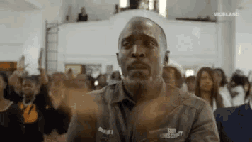 a man with a beard is clapping his hands in front of a crowd of people .
