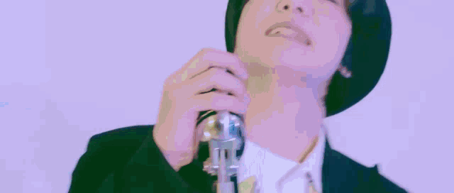 a group of young men are singing into microphones in front of a green background .