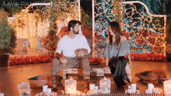 a man and a woman are sitting at a table with candles and flowers .