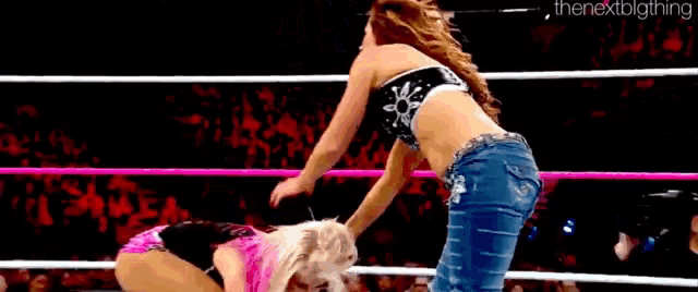 two women are wrestling in a wrestling ring and one of them is kneeling down .