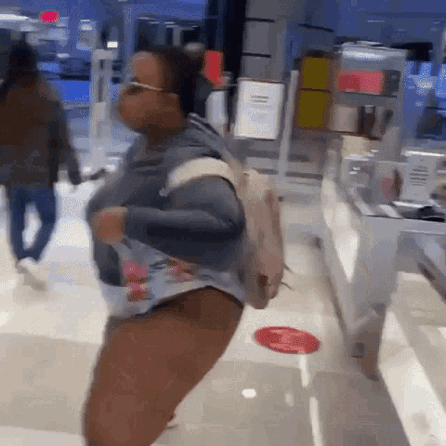 a woman wearing shorts and a backpack is walking through a store .