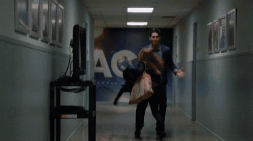 a man and a woman are walking down a hallway with cnn written on the wall behind them