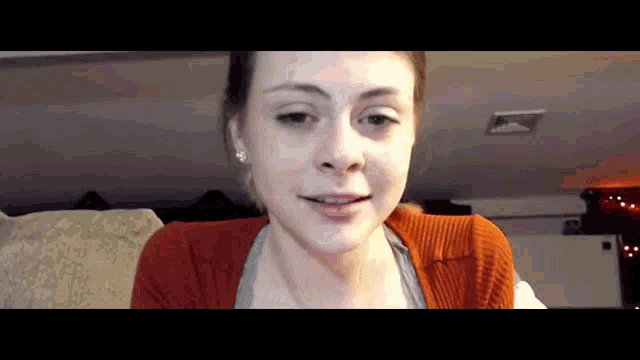 a woman wearing a red sweater and earrings smiles for the camera
