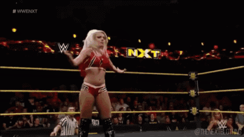 a woman is standing in a wrestling ring with a referee watching .