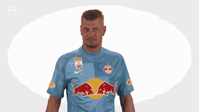 a man wearing a blue shirt with a red bull on the front
