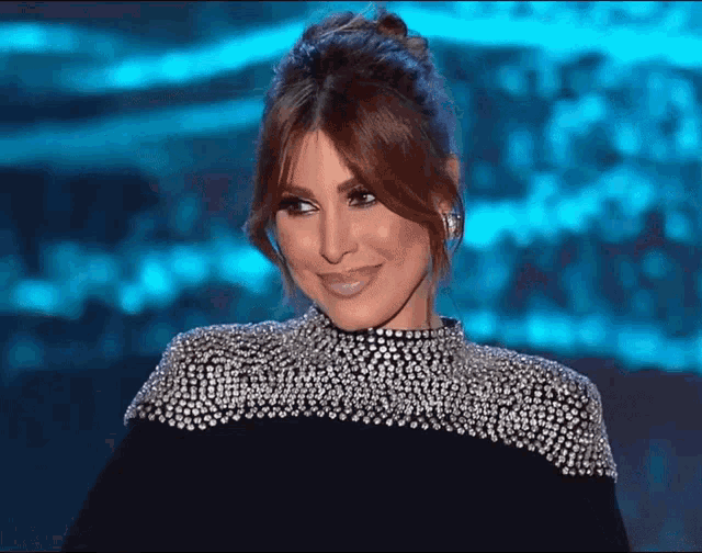 a woman wearing a black and silver dress with rhinestones on the sleeves