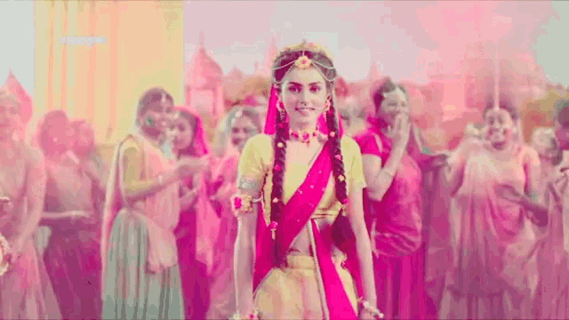 a woman in a pink dress is standing in front of a crowd of women .