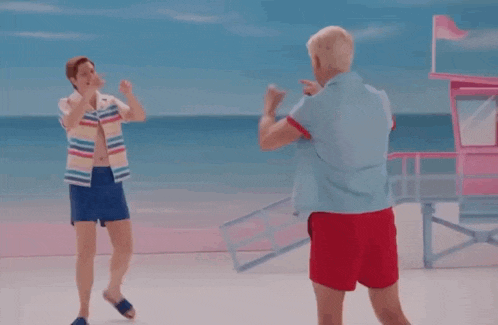 two men are standing next to each other on a beach .