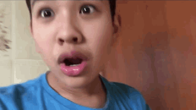 a young boy wearing a blue shirt is making a funny face .