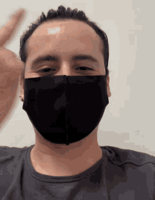 a man wearing a black face mask is waving