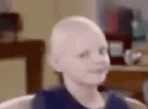 a baby with a bald head is sitting in a chair in a blurry photo .