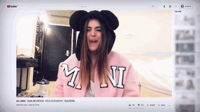 a youtube video of a girl wearing a minnie mouse hat and a pink sweater