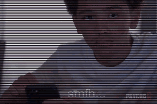 a man in a white shirt is looking at a cell phone with the word smith written on the screen