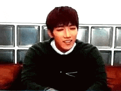 a young man in a black sweater is sitting on a couch .