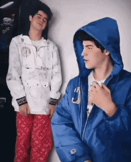 a man wearing a blue champion jacket is standing next to another man