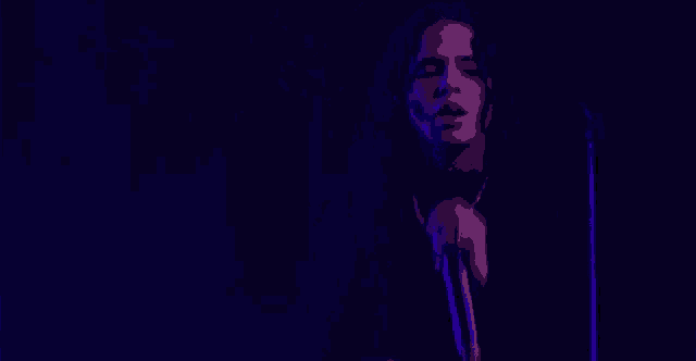 a man with dreadlocks is singing into a microphone on a stage .