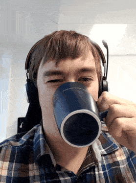 a man wearing headphones is drinking from a blue cup