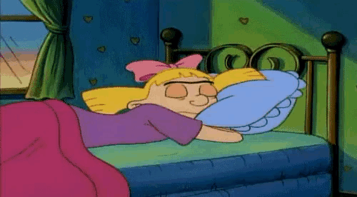 a cartoon girl is sleeping on a bed with a blue pillow