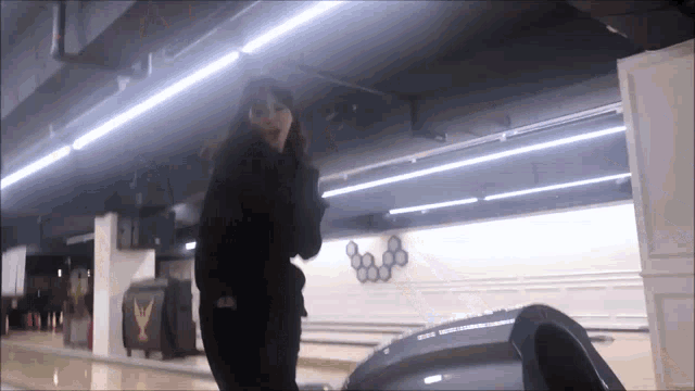 a woman is standing in a bowling alley with a sign that says olympics on it