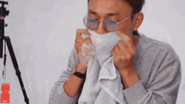 a man wearing sunglasses is holding a plastic bag over his face