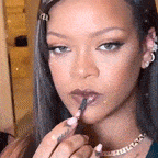 a close up of a woman applying lip gloss with a brush .