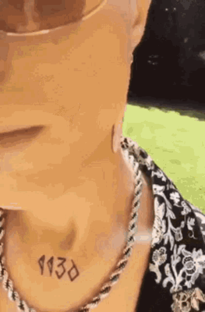 a close up of a person 's neck with a tattoo on it and a necklace .