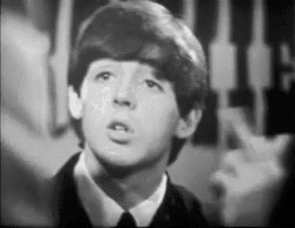 a black and white photo of a young man in a suit and tie looking up .