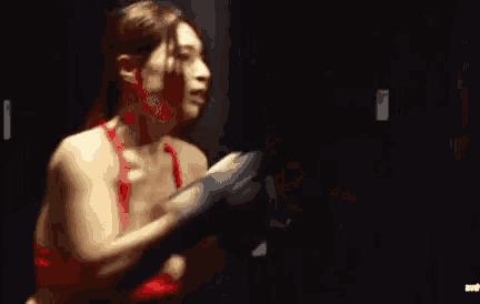 a woman in a red bikini is standing in a dark room with her arms outstretched .