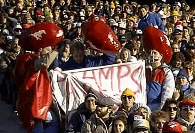 a crowd of people are gathered in a stadium holding a banner that says amps .
