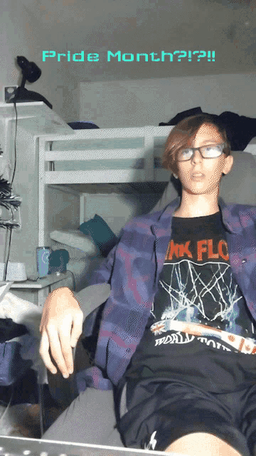 a boy wearing a pink floyd shirt is sitting in front of a bunk bed