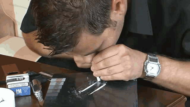 a man is sniffing a line of cocaine while wearing a watch