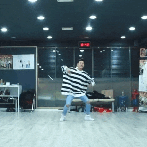a man in a black and white striped shirt is dancing in a room with a digital clock that reads 8:43