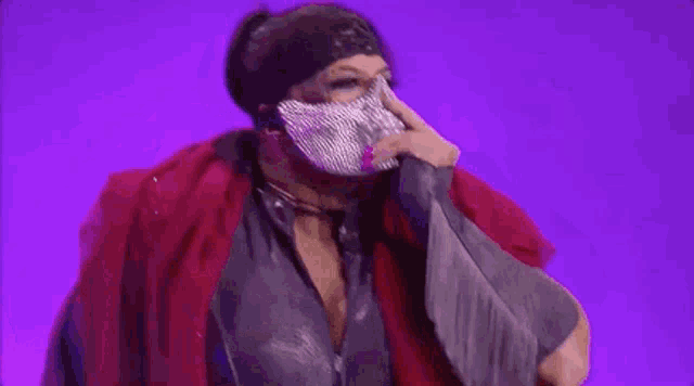 a woman wearing a mask and a red scarf is standing on a stage .