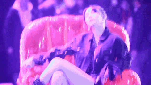 a woman in a black jacket is sitting on a red couch with her legs crossed