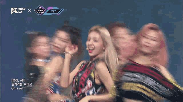 a group of women are dancing on a stage in front of a sign that says " itzy "
