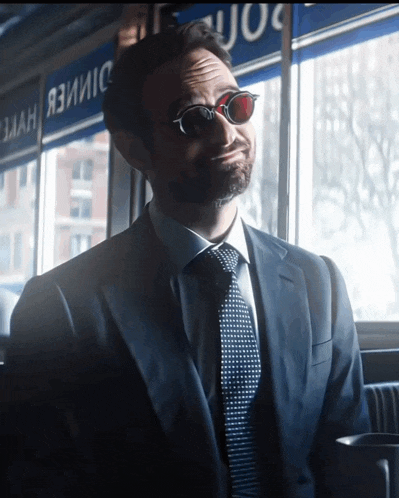 a man in a suit and tie is sitting in front of a window with a sign that says dimer